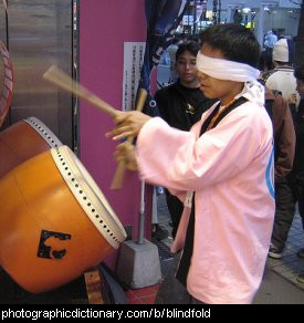 Photo of a boy drumming blindfolded.