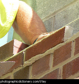 Photo of someone laying a brick