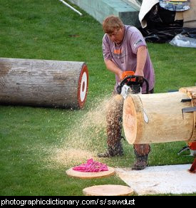 Photo of a man making sawdust by cutting wood.