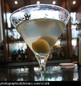 Photo of an olive in the bottom of a martini glass