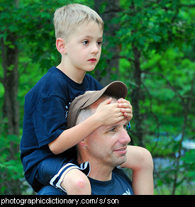 Photo of a boy having a piggyback ride on his father's shoulders